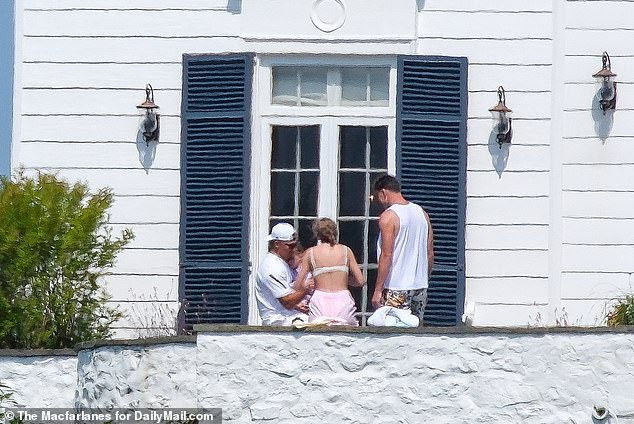 Travis Kelce (R) and Taylor Swift (C) sit with Patrick Mahomes on the mansion's balcony